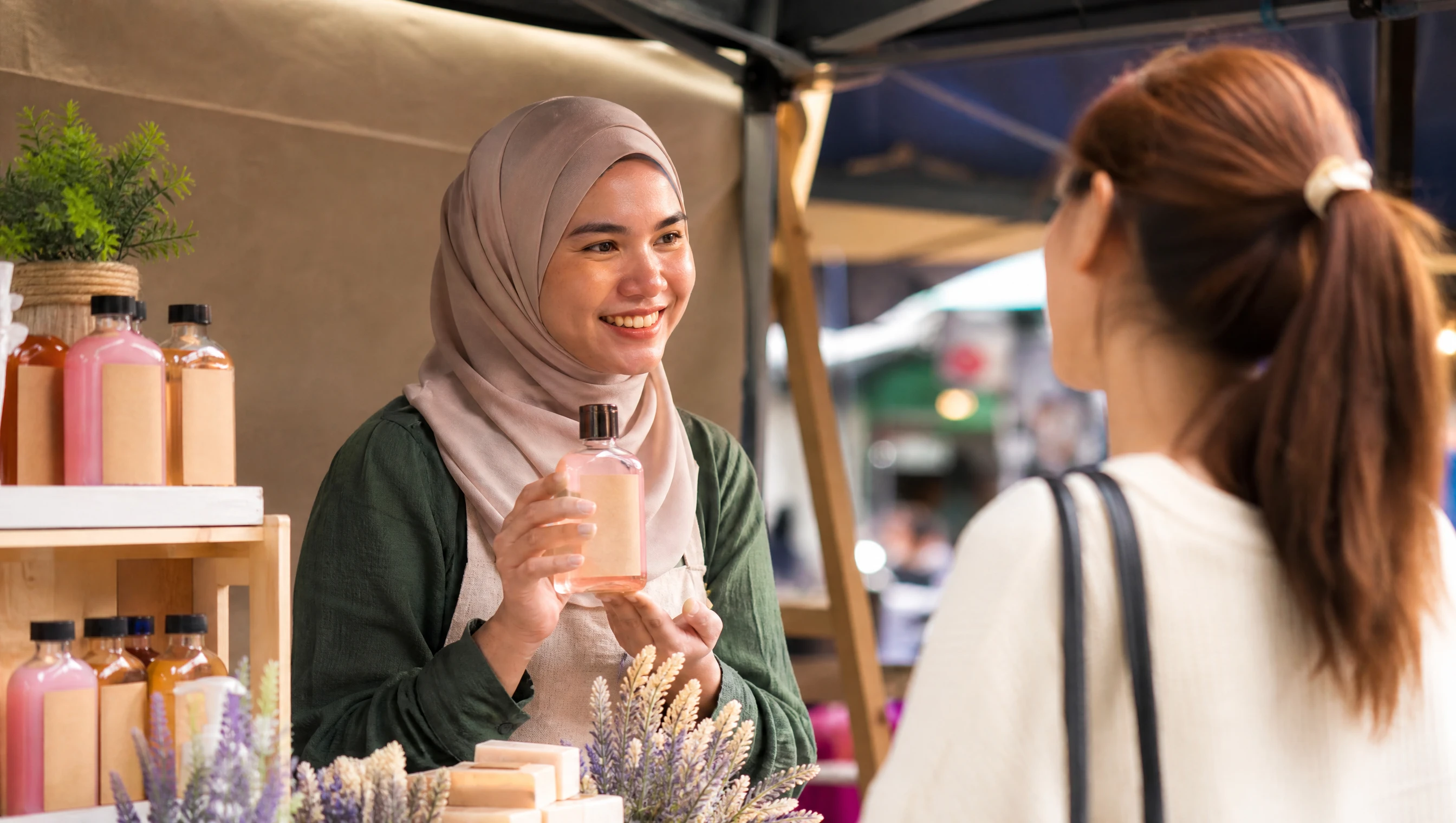 Usahawan wanita Malaysia menunjukkan produk berjenama kepada pelanggan di pasar kecil