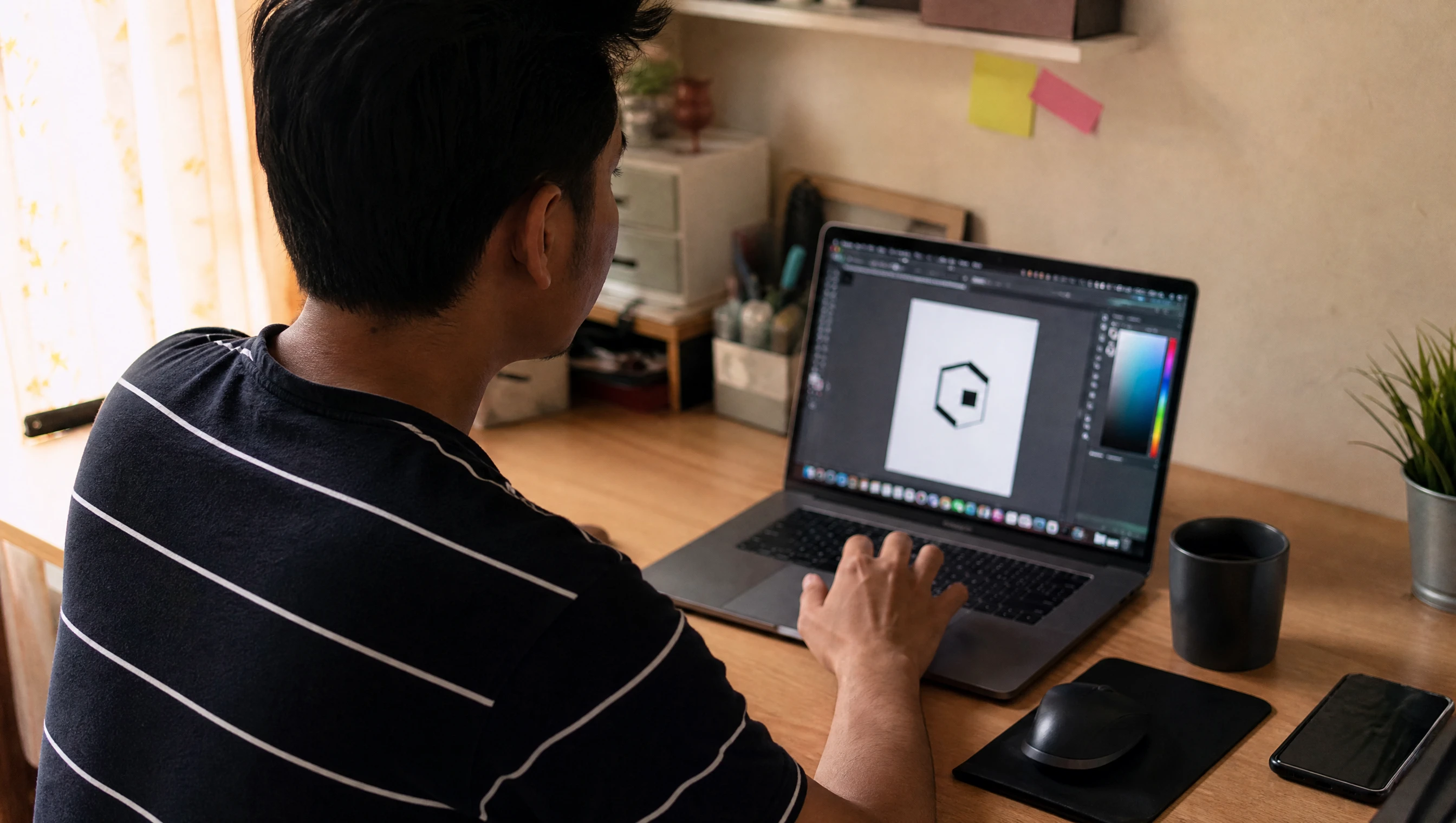 Usahawan Malaysia menggunakan aplikasi design pada laptop untuk membuat logo