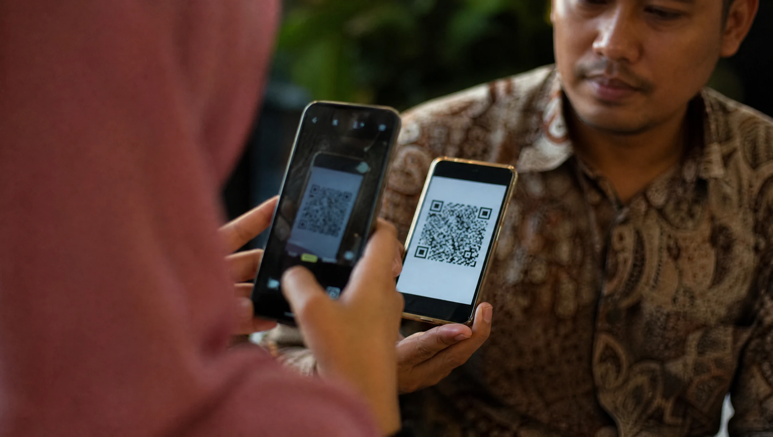 Tangan pelanggan Malaysia scan DuitNow QR di skrin telefon untuk bayar pembelian online
