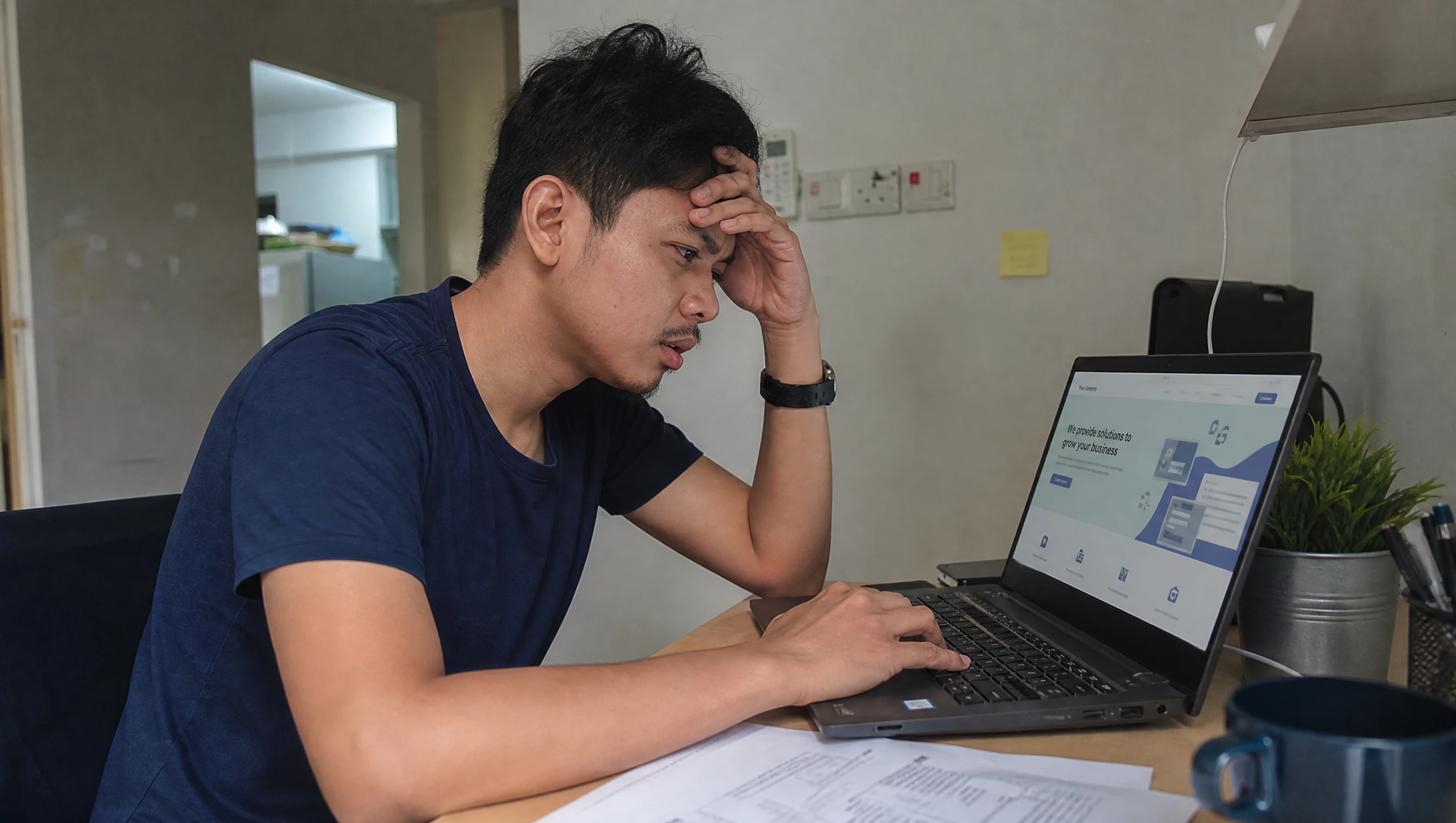 Pemilik perniagaan kecil Malaysia melihat website mudah pada skrin laptop di meja kerja di rumah