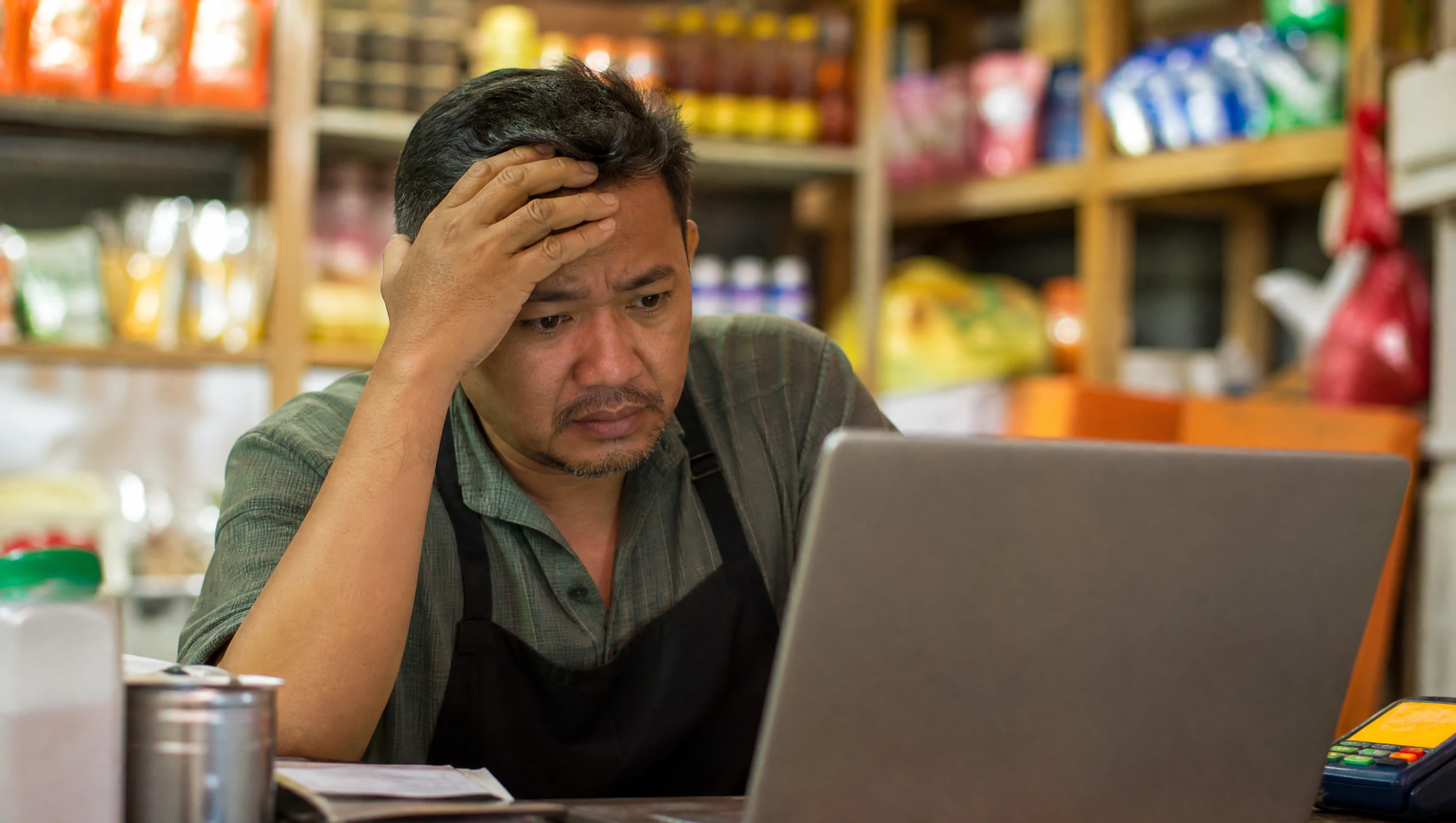 Pemilik kedai Malaysia kelihatan risau melihat masalah pada laptop di kedainya