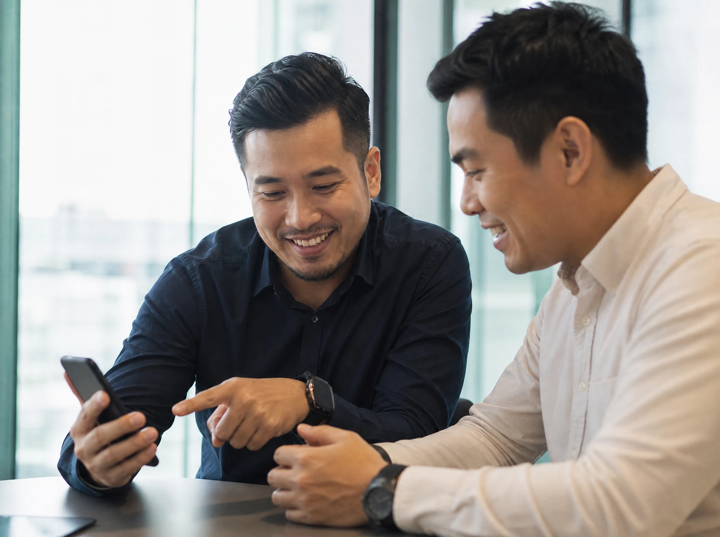 Malaysian developer showing a client their new app on a phone