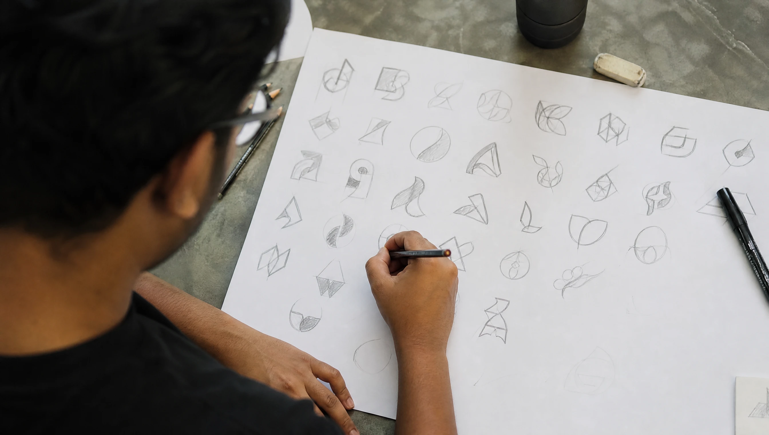 Malaysian designer sketching many logo concept thumbnails