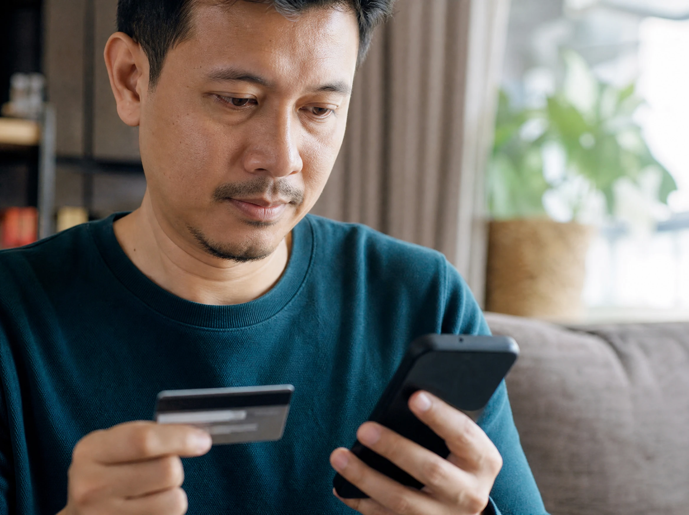 Malaysian man completing a secure checkout on his phone with a card