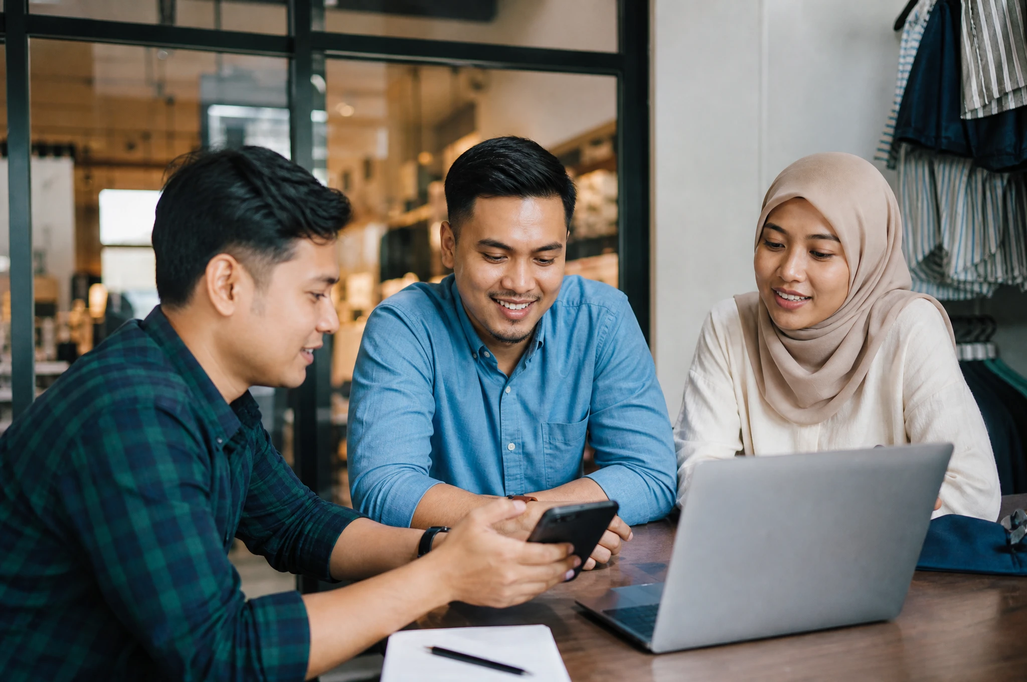 Malaysian app team consulting with a retail client over a laptop and phone