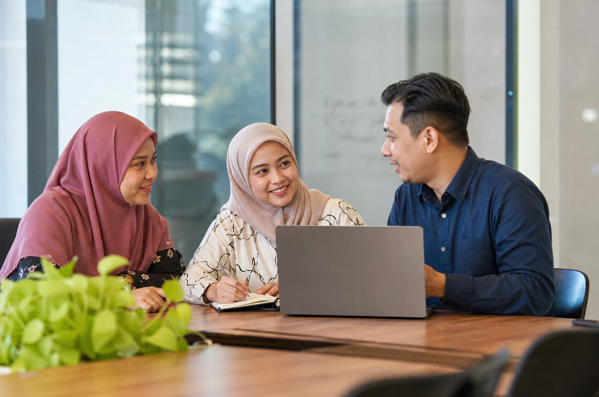 Friendly Malaysian team consulting with a small business client over a laptop