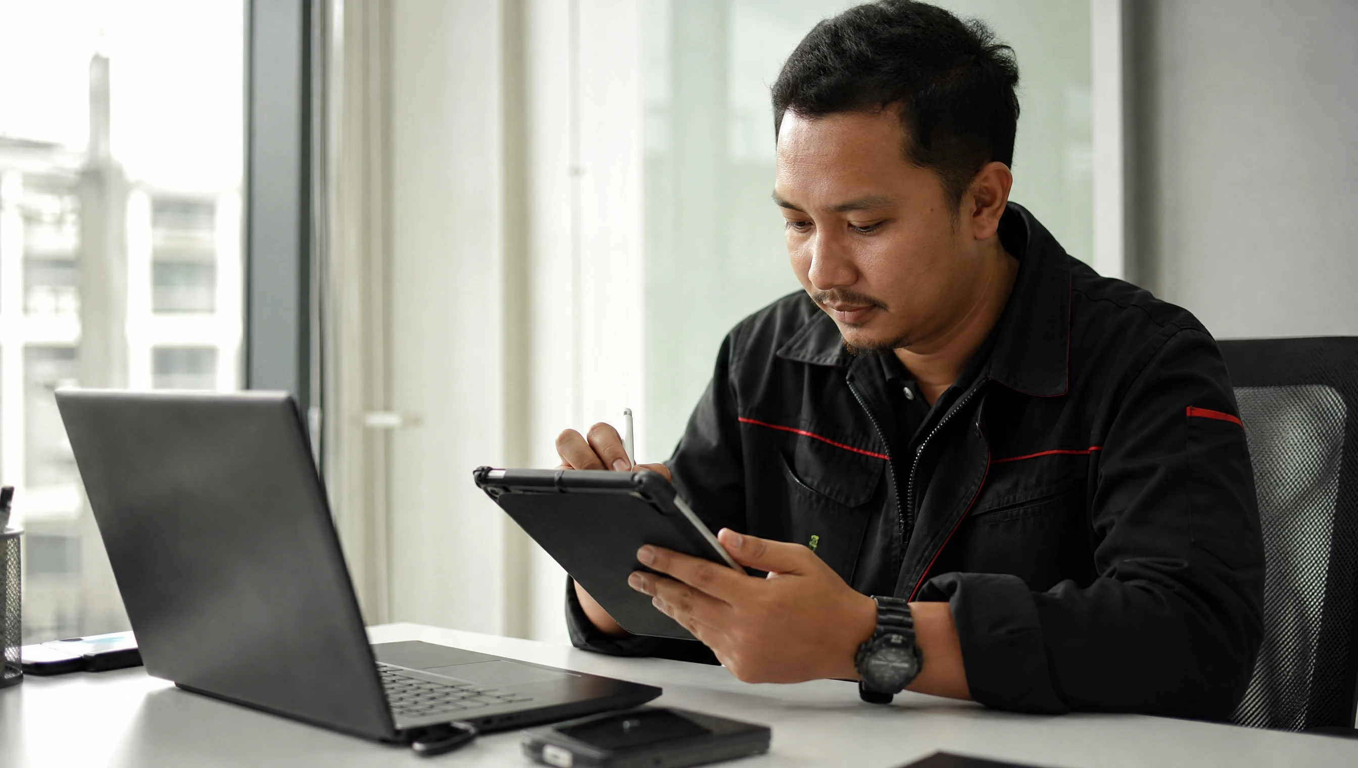 Malaysian technician performing scheduled maintenance on a tablet