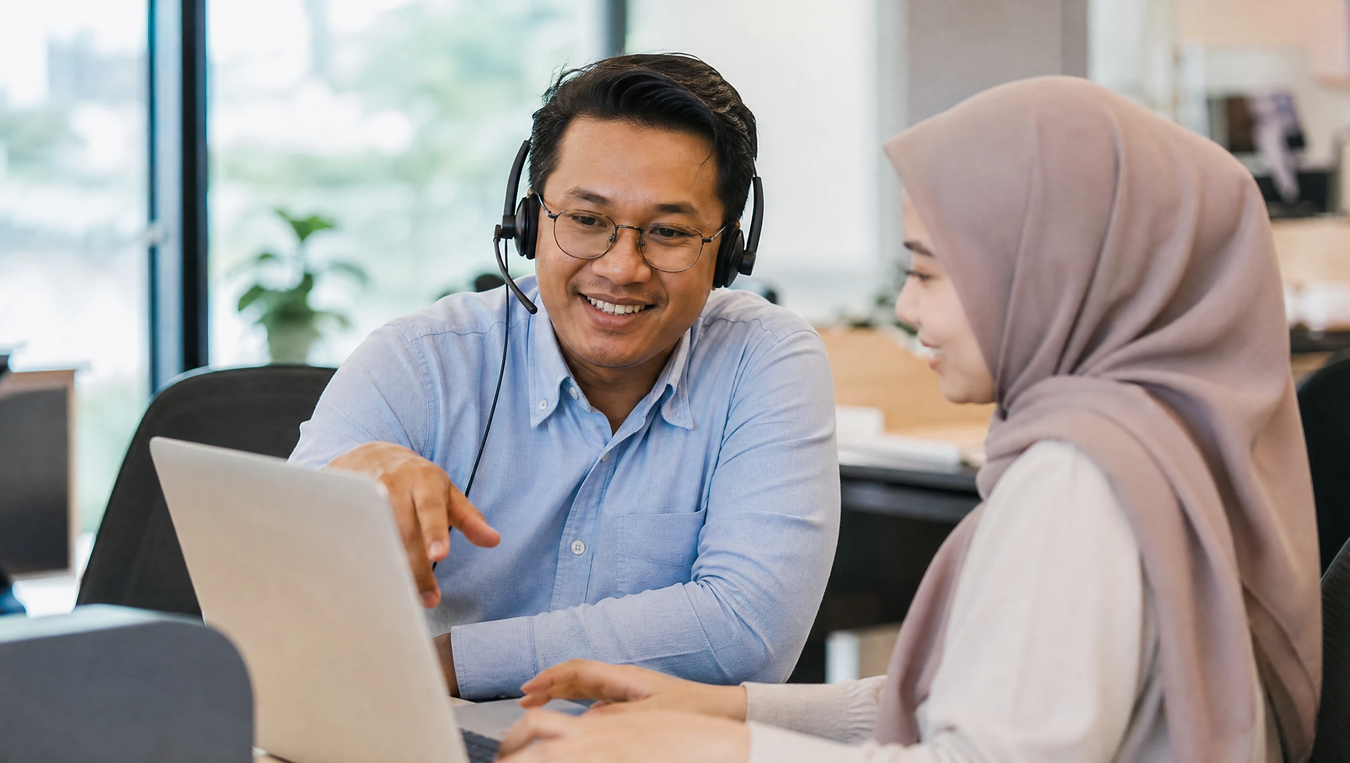 Malaysian support agent with a headset helping a customer