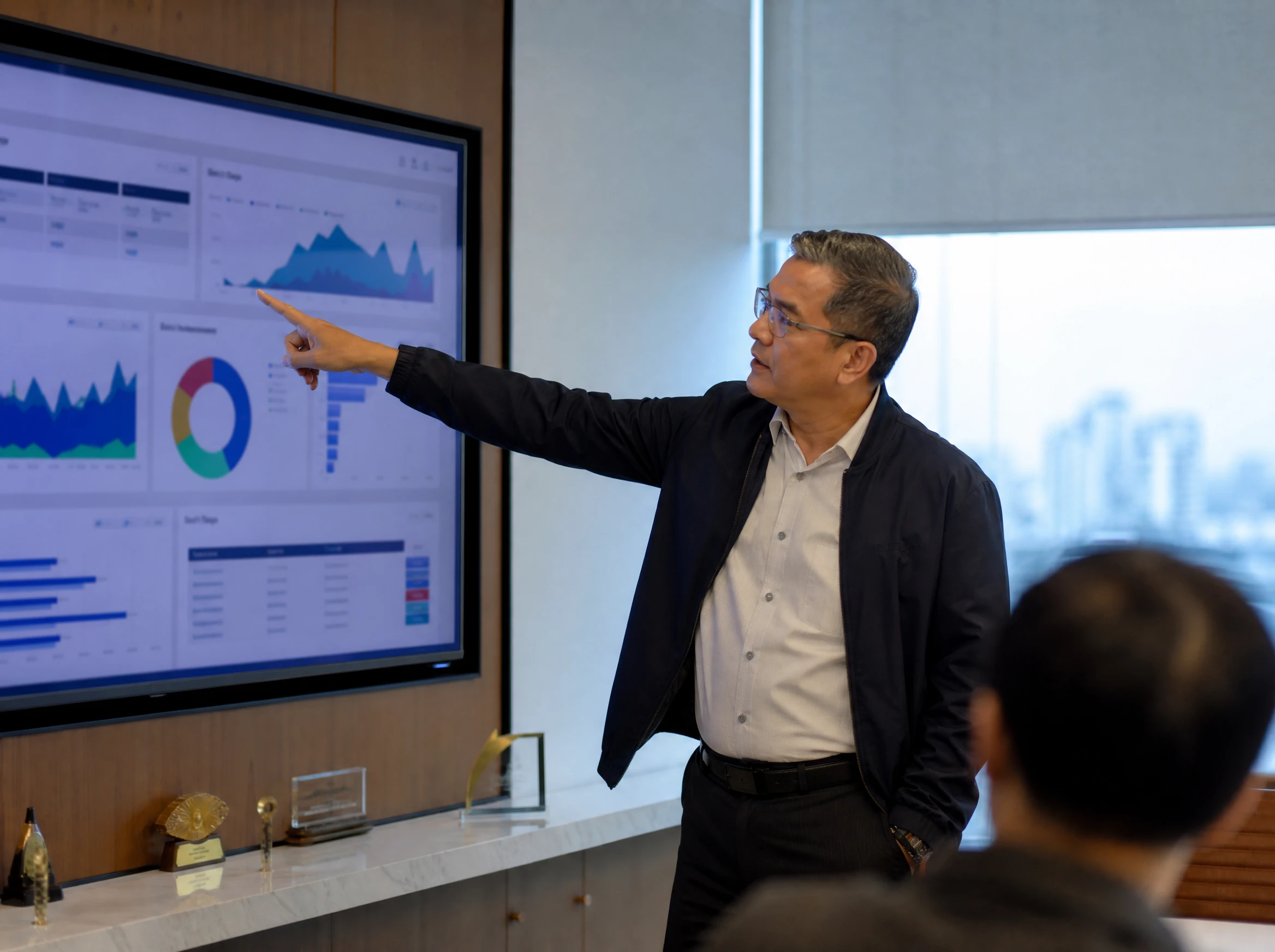 Malaysian manager reviewing an operations dashboard on a wall screen