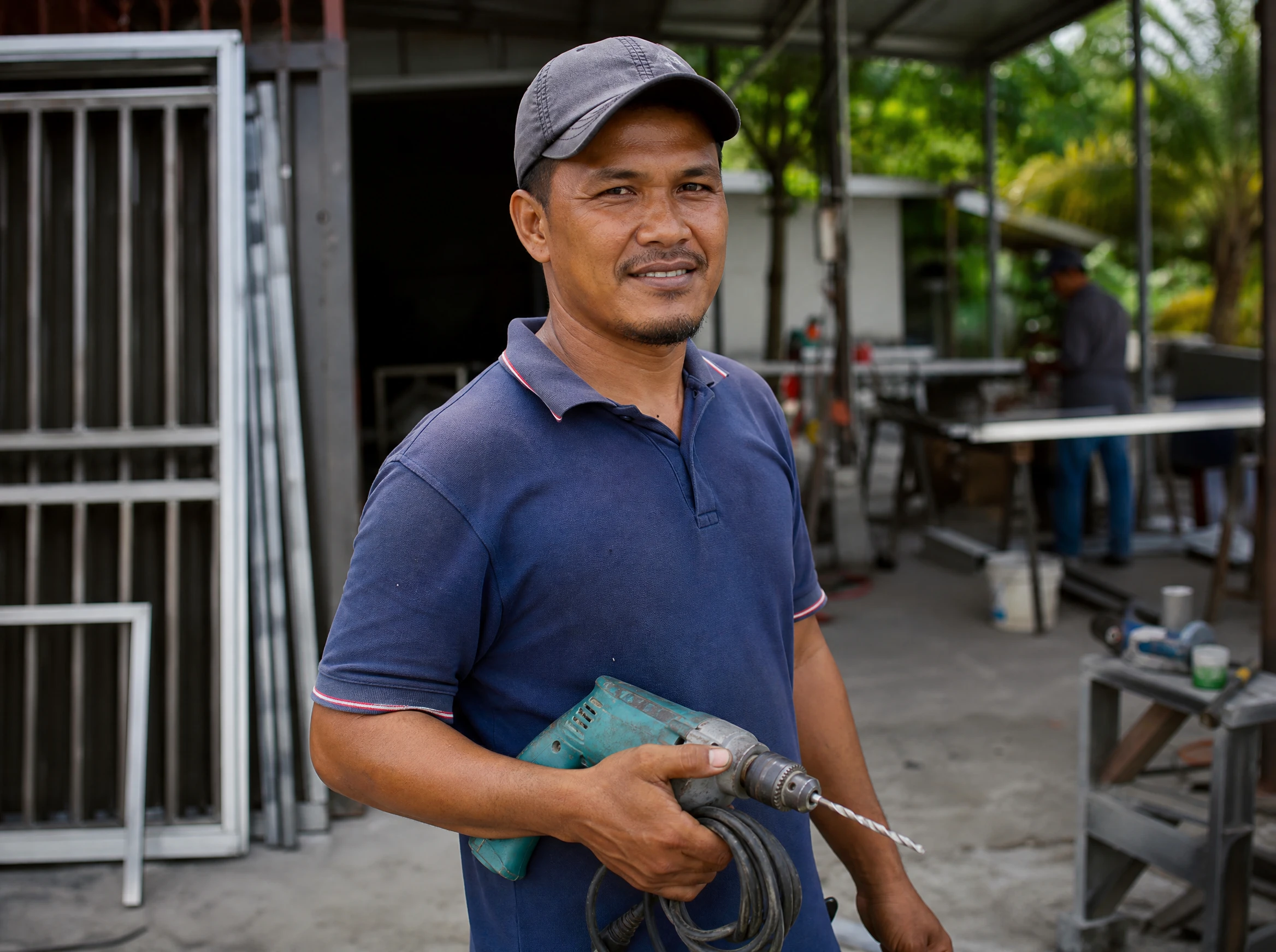 Malaysian contractor holding tools at a workshop