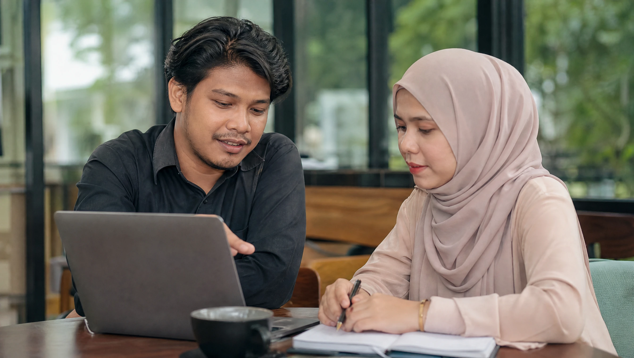 Malaysian designer and client discussing a website project over a laptop