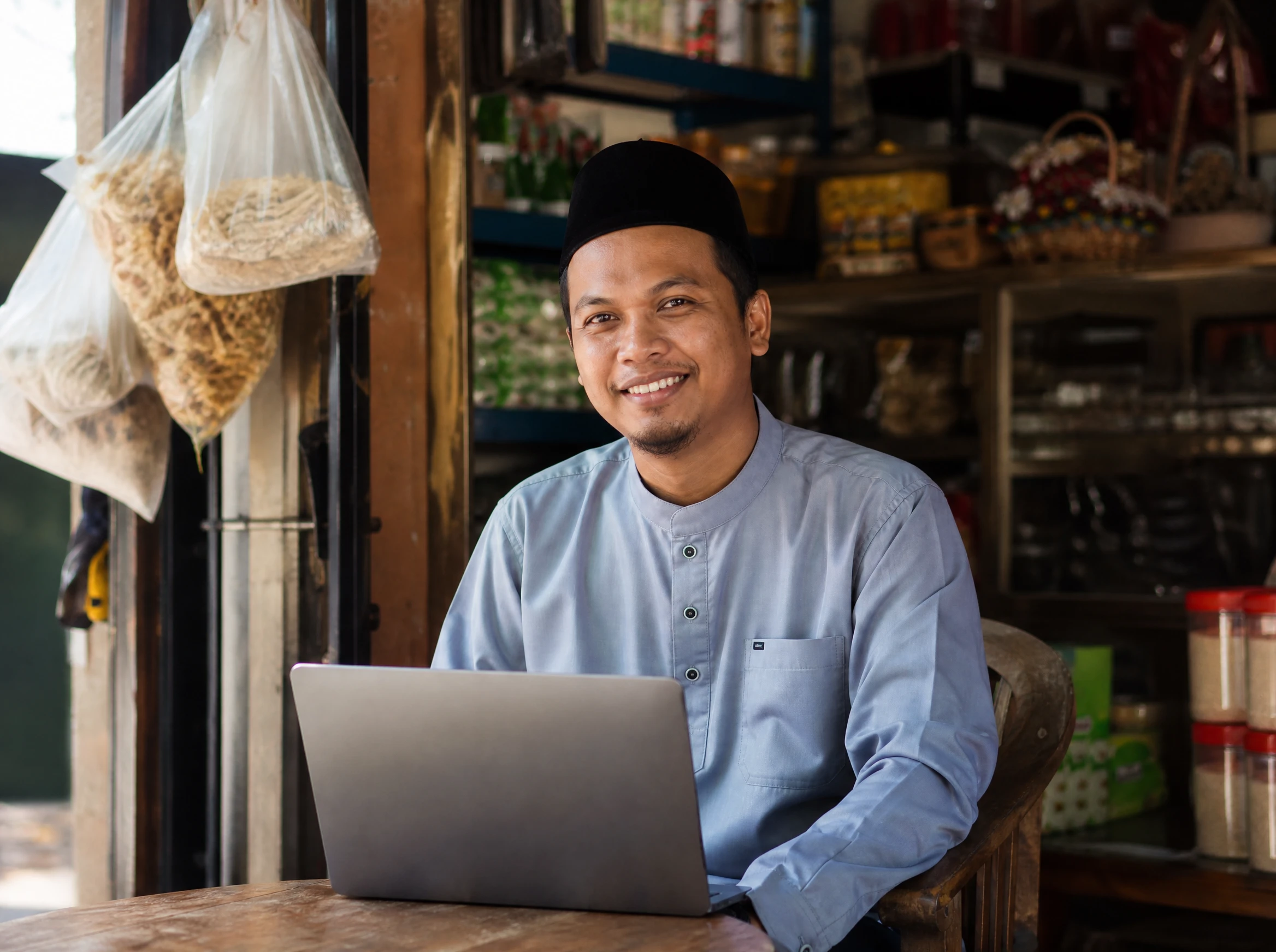 Confident Malaysian small business owner with a laptop in his shop