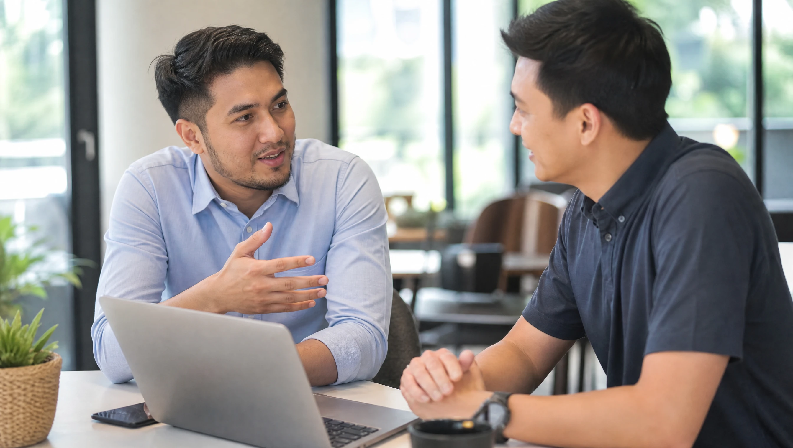 Malaysian developer and client discussing a project over a laptop