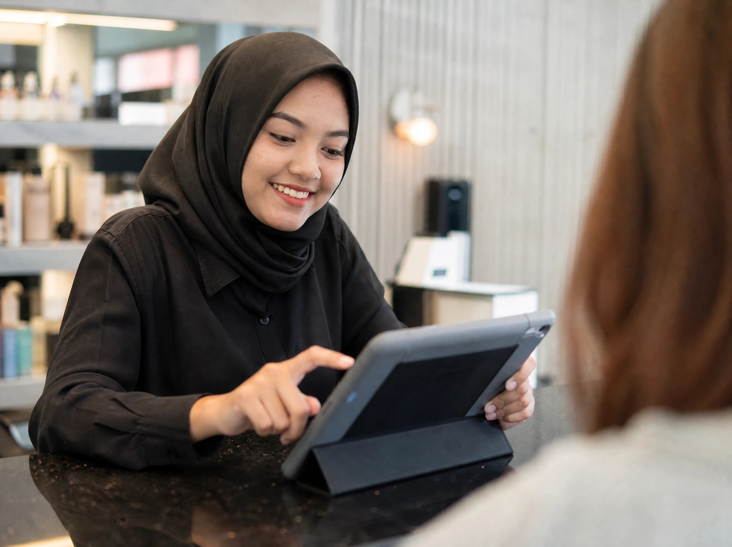Malaysian receptionist using a booking system on a tablet