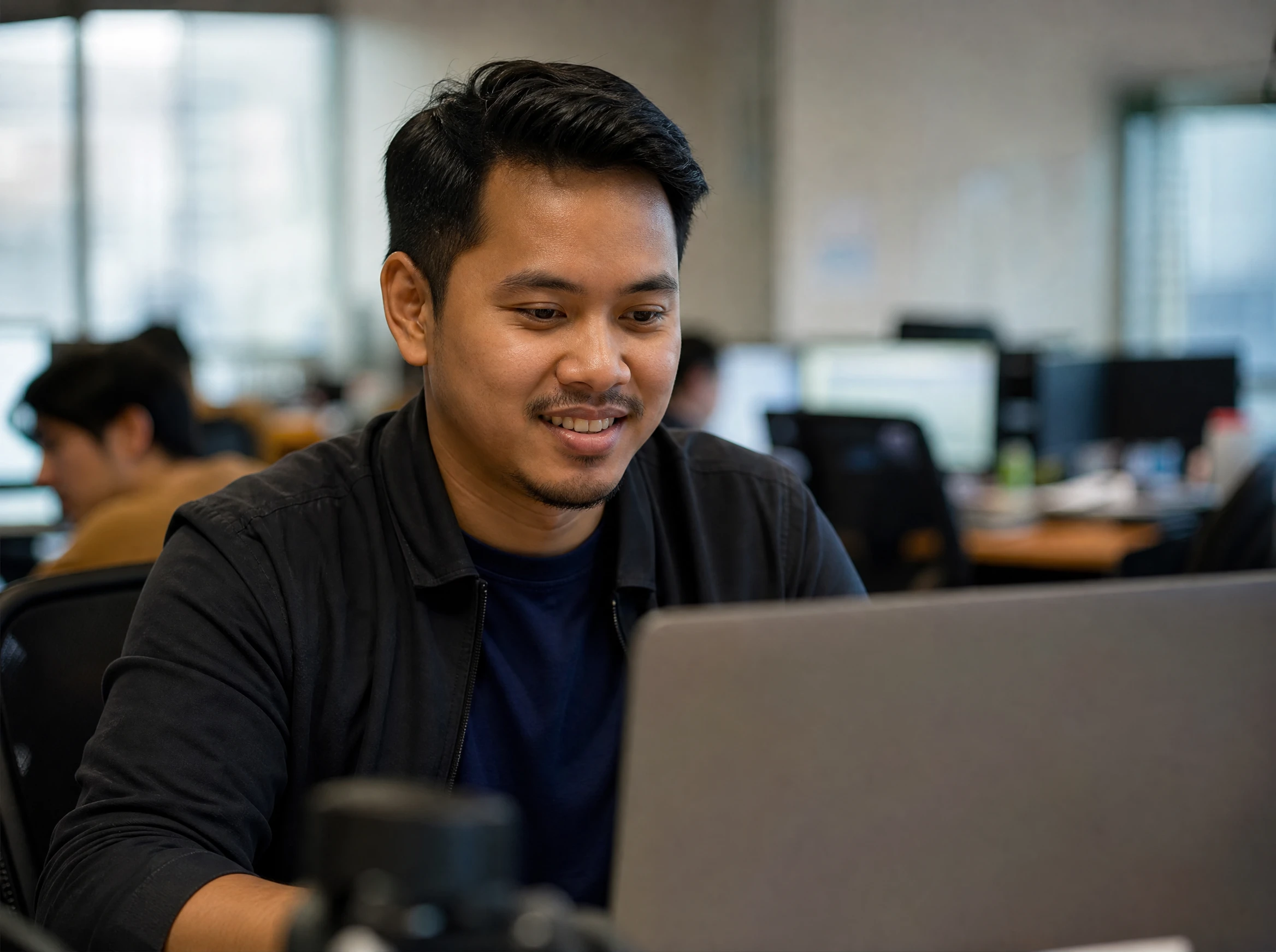 Confident Malaysian software team lead at a laptop