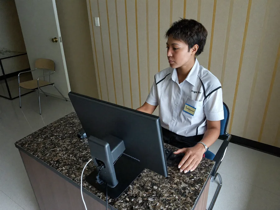Clinic receptionist using a desktop computer at a Malaysian clinic
