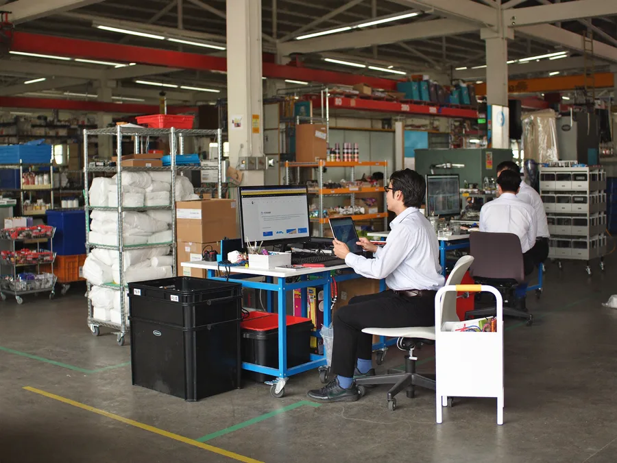Malaysian factory supervisor checking stock on a desktop terminal