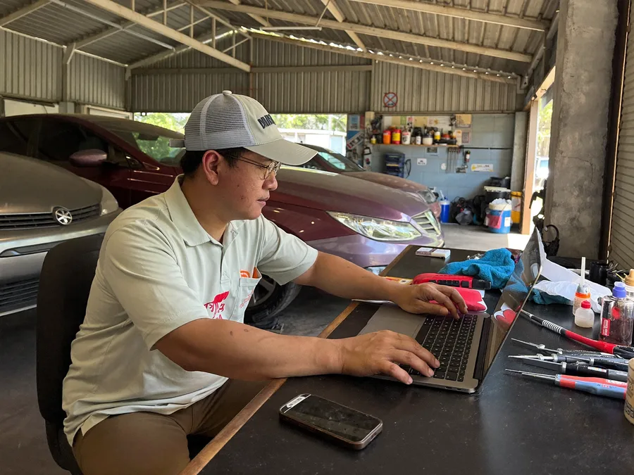 Malaysian workshop owner using a computer in the workshop office