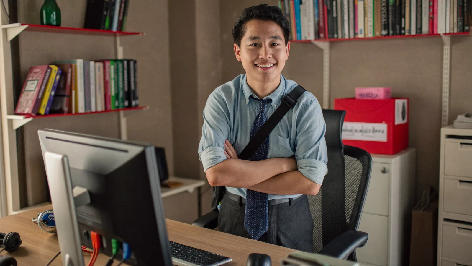 Confident Malaysian business owner beside a PC running his custom desktop software